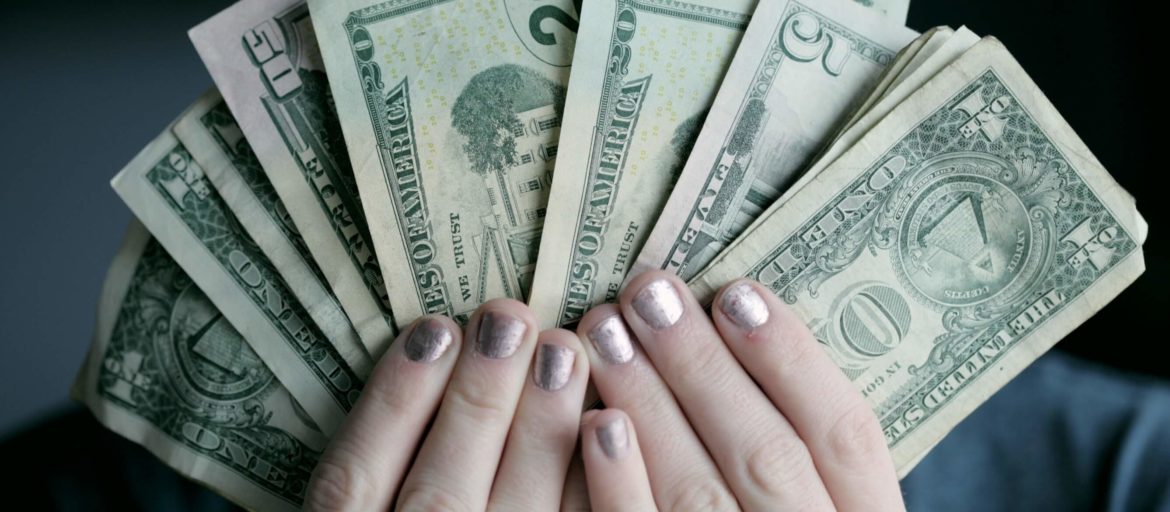 Hands of a woman with gold metallic nail polish holding money