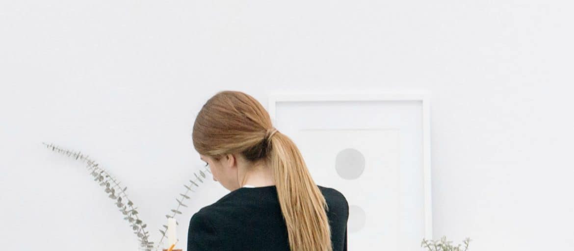 A woman sitting at a white desk writing in a journal