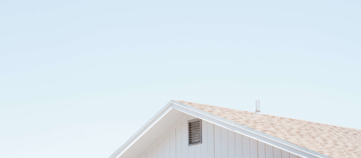 Top of a house with framing and a peaked roof with a blue sky background