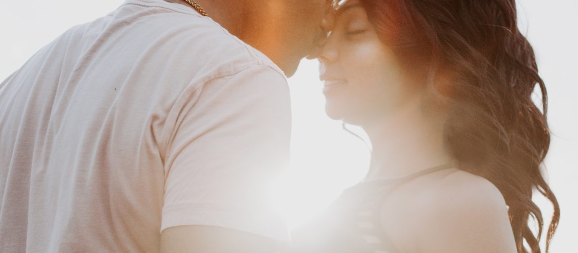 Couple hugging in front of a sunset on a beach